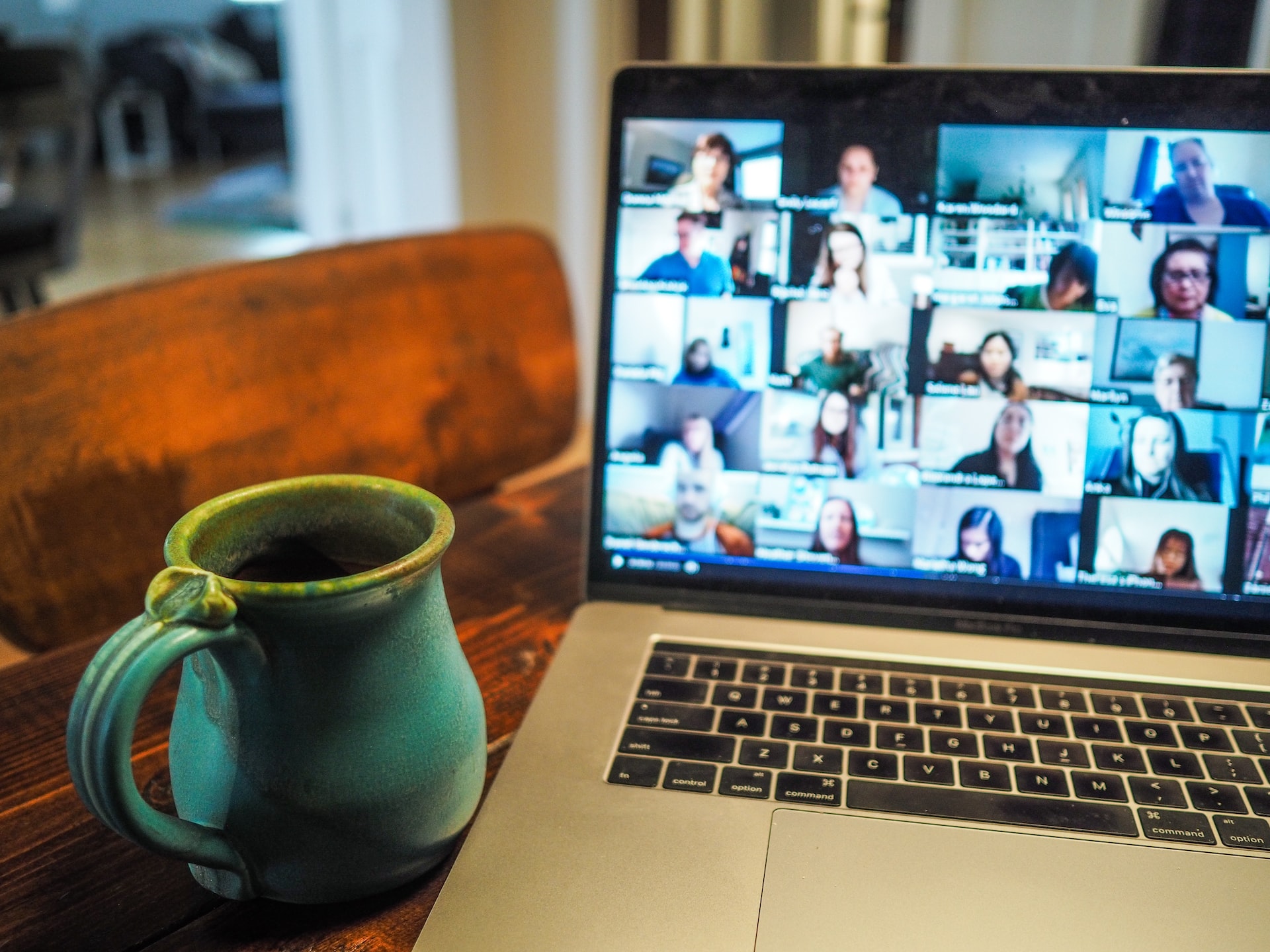 An image of the home office of a remote worker, where his mac laptop screen displays a Zoom meeting